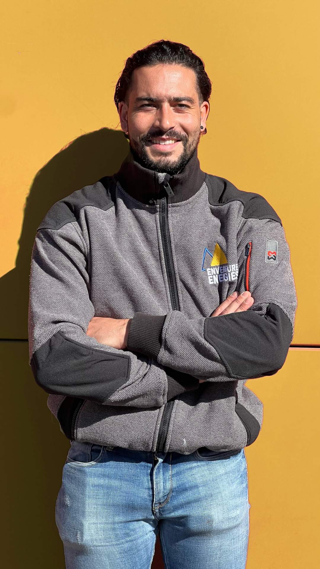 Mael, dirigeant d'Envergure Énergies, bras croisés devant un mur jaune